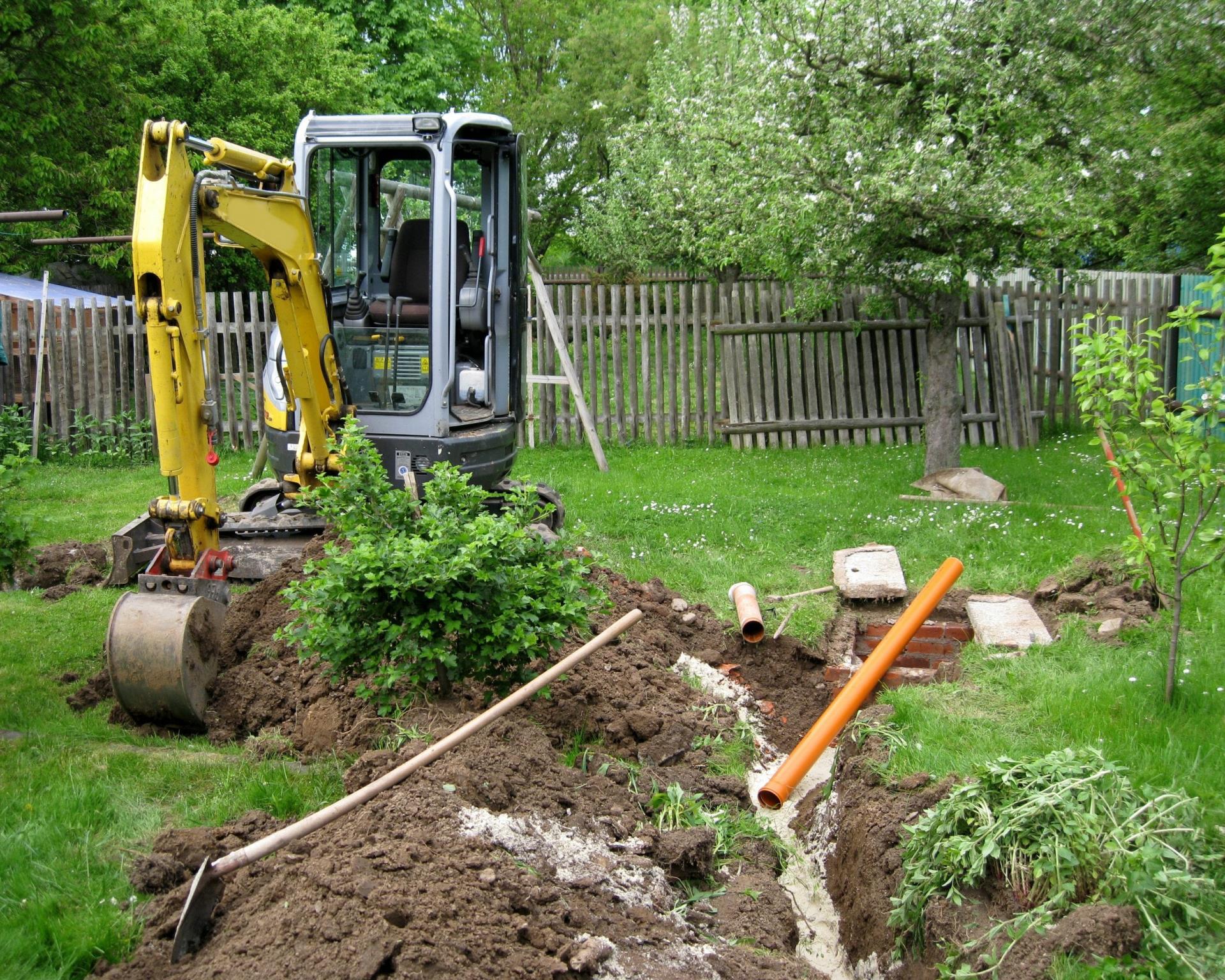 Backhoe digging a trench in a backyard