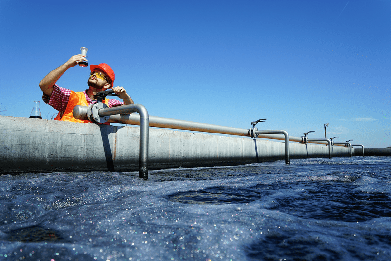 Person analyzing water sample while leaning on a pipe